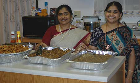 Bhargavi and her mother infront of trays of Pakoras, Chicken kurma and Egg Kurma