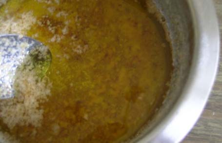 Removing the solids from the ghee with a spoon