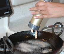 Pressing the dough into muruku shape using muruku maker into hot oil